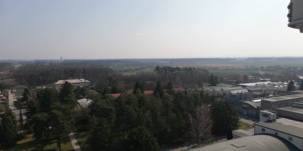 Pohled na Zvěřínek s lesy a průmyslovými objekty v pozadí.