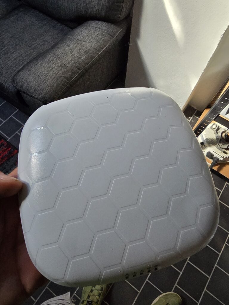 Zařízení WiFi opakovače s hexagonálním vzorem na povrchu.